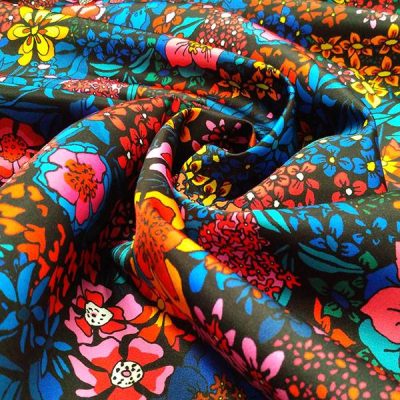 Tessuto abbigliamento stile africano con fiori colorati su base nera