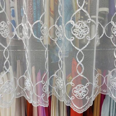 tessuto per tende in tulle ricamato bianco al metro trasparenza appesa con scampoli dietro dettaglio 1