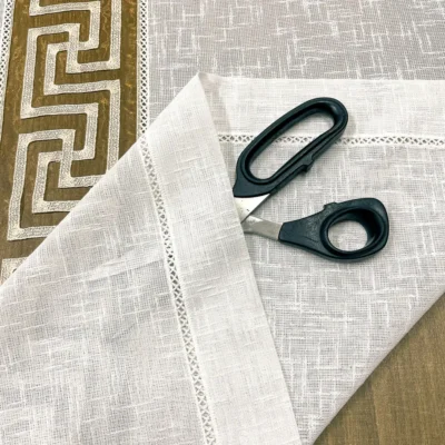 Dettaglio tendina greca con forbici da sarta su tessuto lino naturale