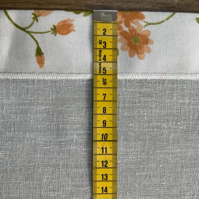 Tendina bianca con bordure fiori e metro da sarta per misurazione