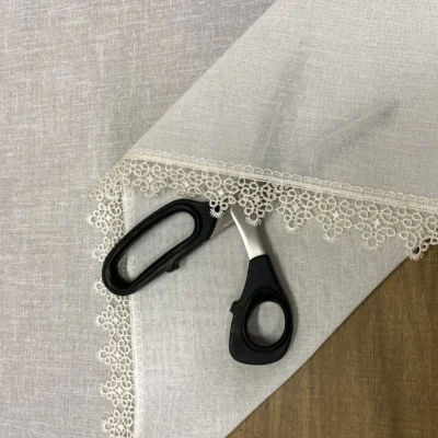 Tendina effetto lino bianca con bordo pizzo macram&egrave; esposta in negozio tessuti