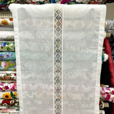 Tendina effetto lino bianco con fascia centrale a rombi esposta in negozio tessuti