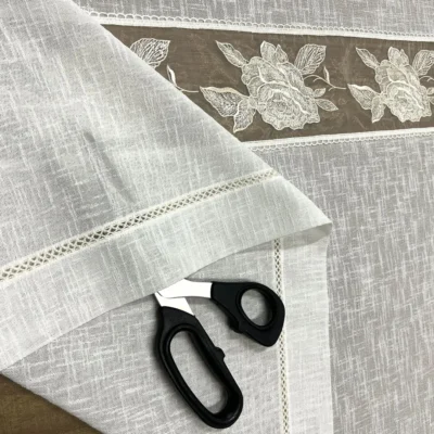 Dettaglio bordo e lavorazione a giorno della tendina effetto lino con fascia centrale ricamata