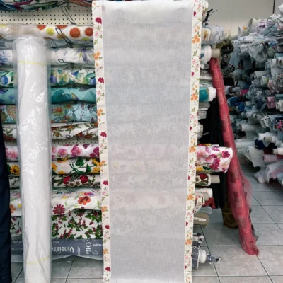 Tendina effetto lino bianca con fiori srotolata su banco da lavoro