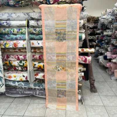 Vista completa della tendina a vetro rosa pesca con pannelli alternati a righe, cerchi e ricami