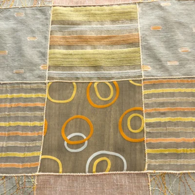 Particolare del tessuto della tendina a vetro con ricami a cerchi arancioni e righe orizzontali gialle