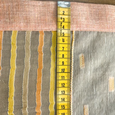 Metro da sarto poggiato su una tendina a vetro per mostrare l'altezza di 15cm del singolo modulo decorativo