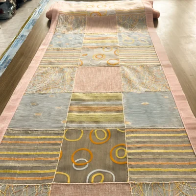 Tendina a vetro tesa su un tavolo da taglio che mostra la sequenza dei moduli decorativi rosa, ocra e grigio